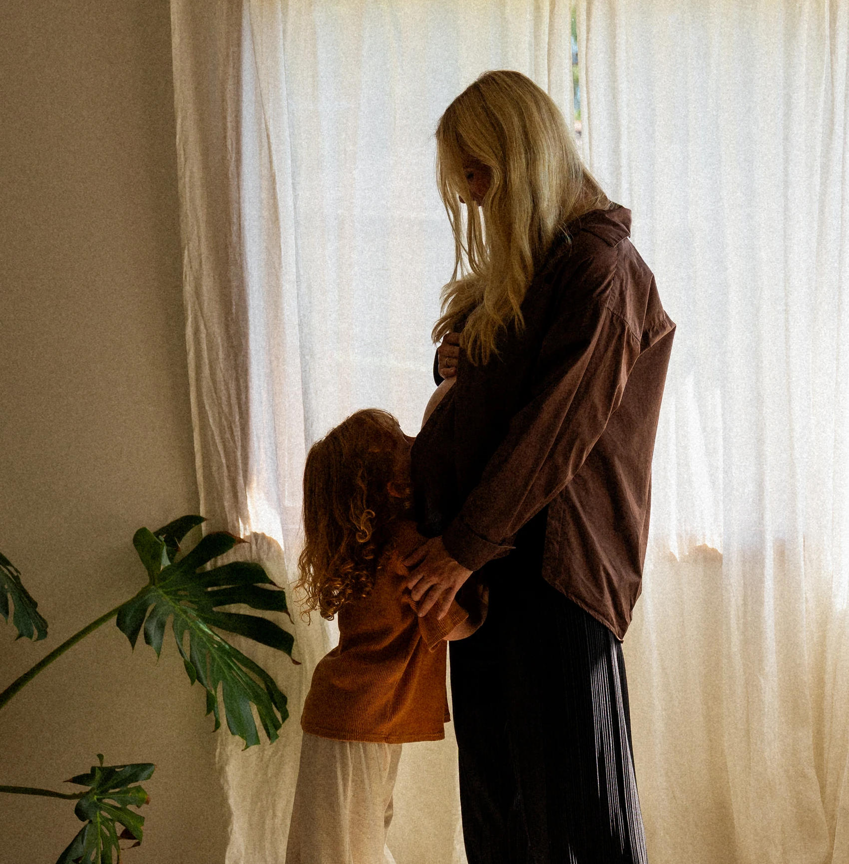 Lani standing at a window with her child leaning into her